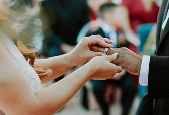 A bride places a wedding band on her new husband's finger.