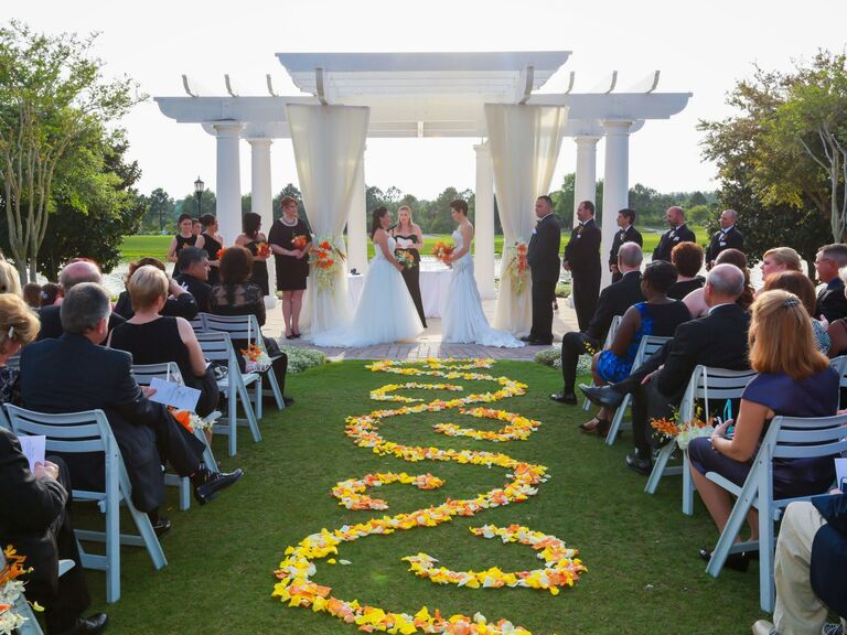 Ceremony aisle lined with orange and yellow flower petals. 