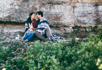 Couple sharing blanket and smiling at eachother on hillside in Texas