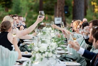 guests toasting with wine and champagne glasses at long table