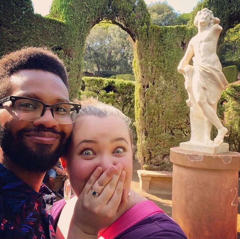 5 days after their 5th anniversary, Spenser took Sam to a quiet park in Barcelona and it immediately started raining. That didn't stop Spenser from getting his knee dirty, and proposing at the center of the labyrinth. She said yes! And then the sun came out!