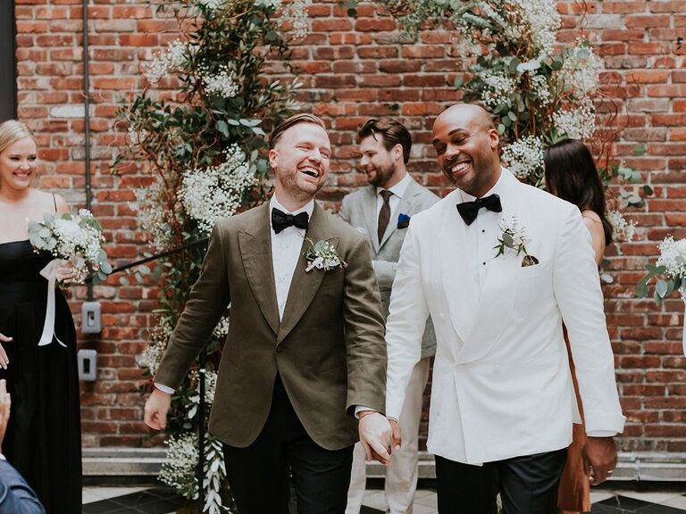 two grooms smiling during wedding recessional