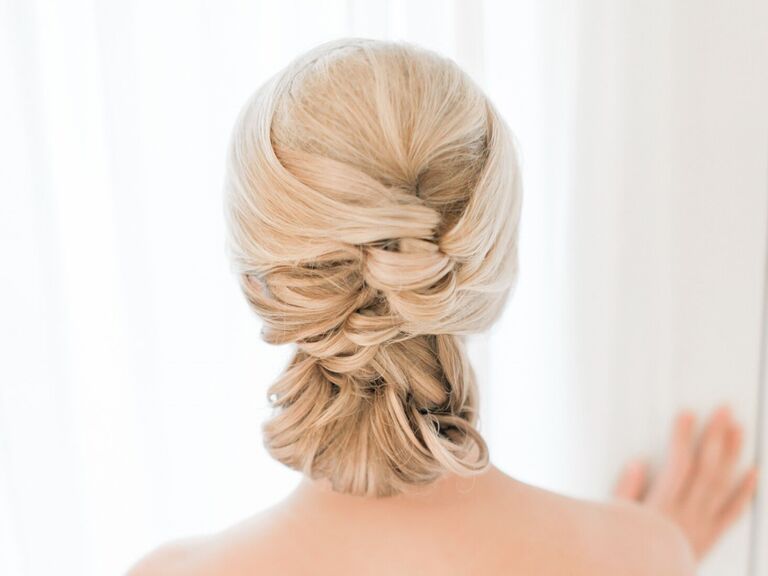 Bride wears her hair in a braided elegant updo. 