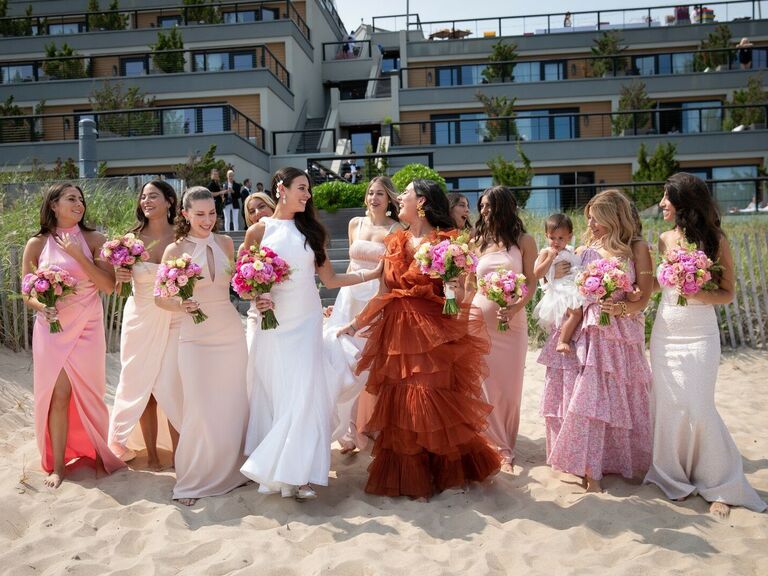 Bride and bridesmaids pose for the camera on the beach. 