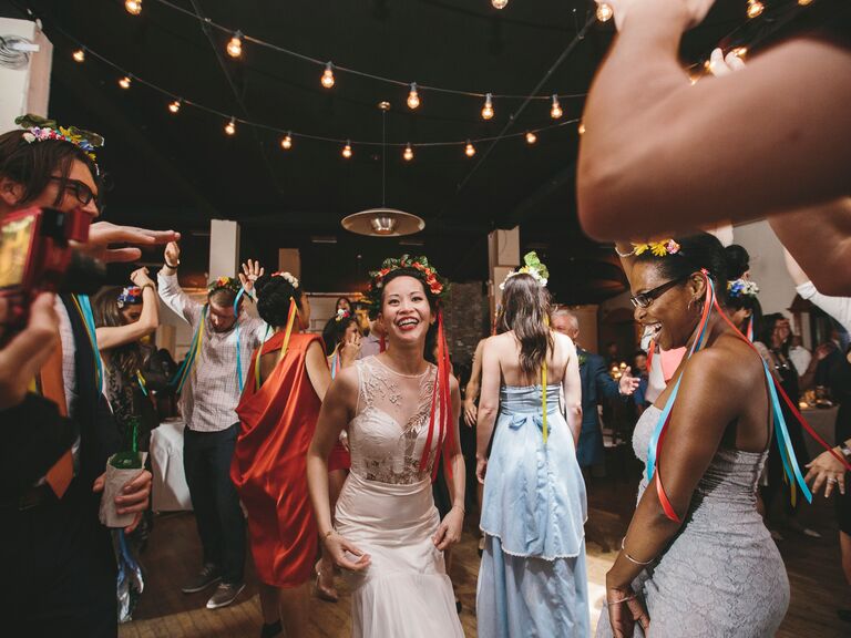 Bride dancing with wedding guests while wearing wedding wreaths.