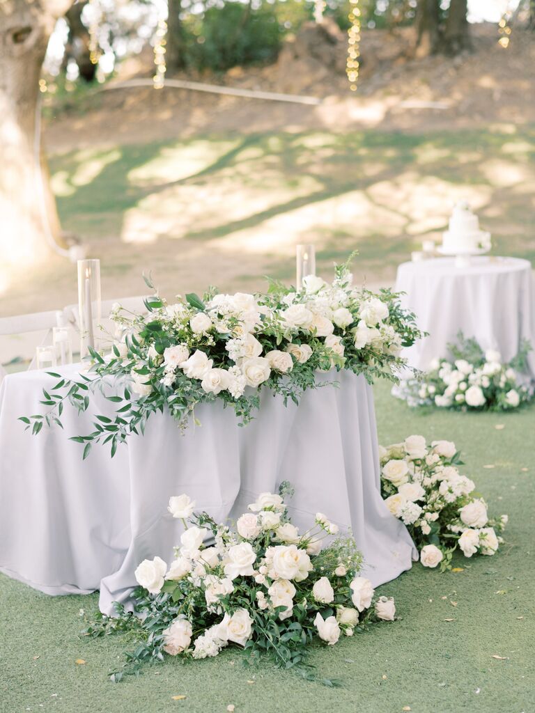 elegant wedding sweetheart table idea with gray tablecloth, gray taper candles and white rose oversized centerpiece with greenery