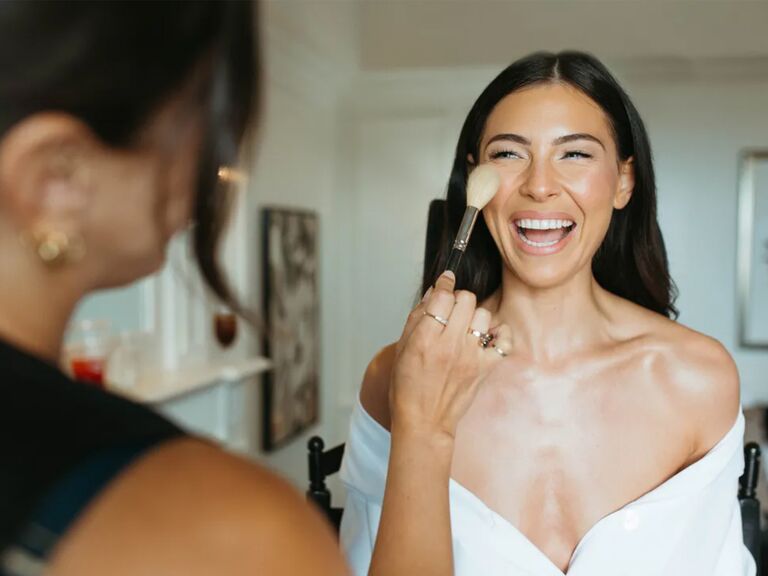 Bride smiling while getting her makeup done