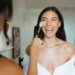 Bride smiling while getting her makeup done