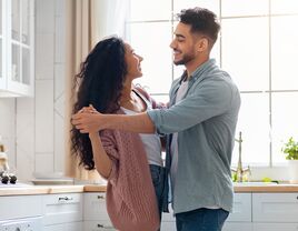 Couple in a committed relationship dancing in the kitchen.