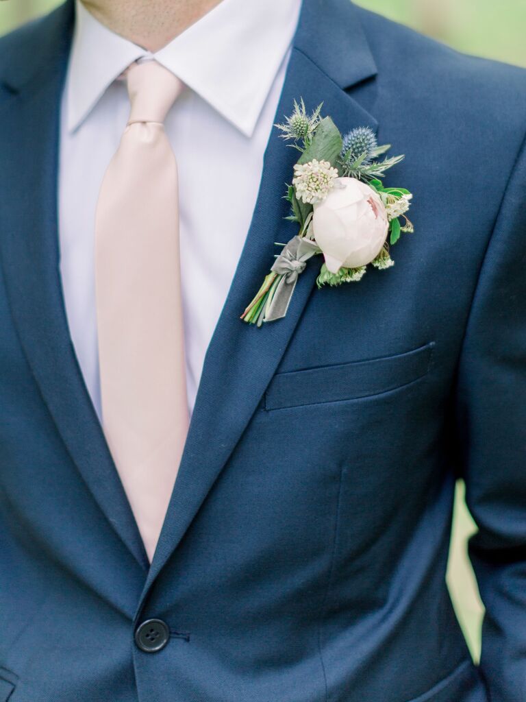 A gentleman wears a dusky blue tux with a boutonniere in pastel colors.