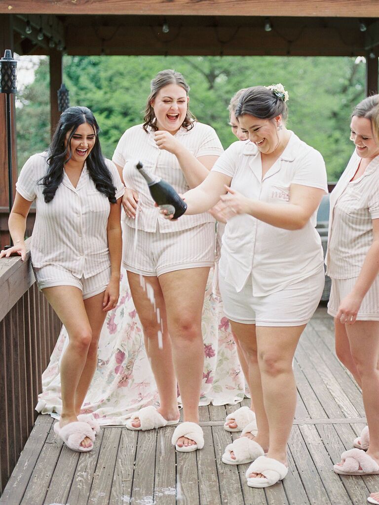 Bridesmaids and bride popping champagne on wedding morning