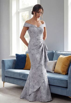 Striking and sculptural, this Gail Jacquard gown is designed to showcase both fabric and form for the Mother of the Bride. The rich Jacquard fabric adds depth and dimension, while the off-the-shoulder portrait neckline creates a beautifully framed, sophisticated look. Crafted in a flattering fit-and-flare shape, soft gathers draw to the side and cascade down the front of the skirt, enhancing the silhouette with elegant movement and drama. Confident, polished, and refined, this gown makes a powerful and memorable statement.
