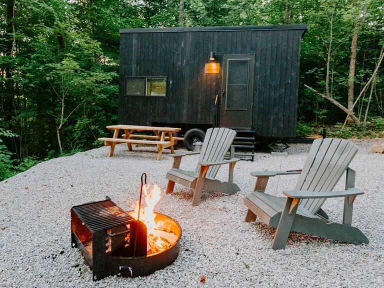 Cabin getaway with two lawn chairs and fire pit in woods anniversary gift for couples who have everything