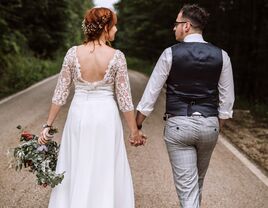 Bride in backless gown and groom holding hands