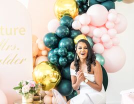 Bride sitting in front of teal-and-pink balloon installation