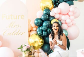 Bride sitting in front of teal-and-pink balloon installation
