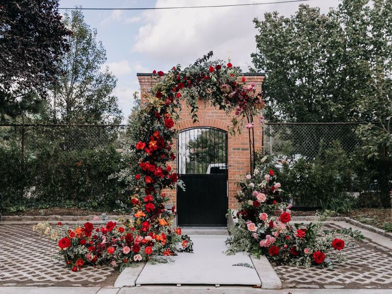Arch in courtyard covered in red roses