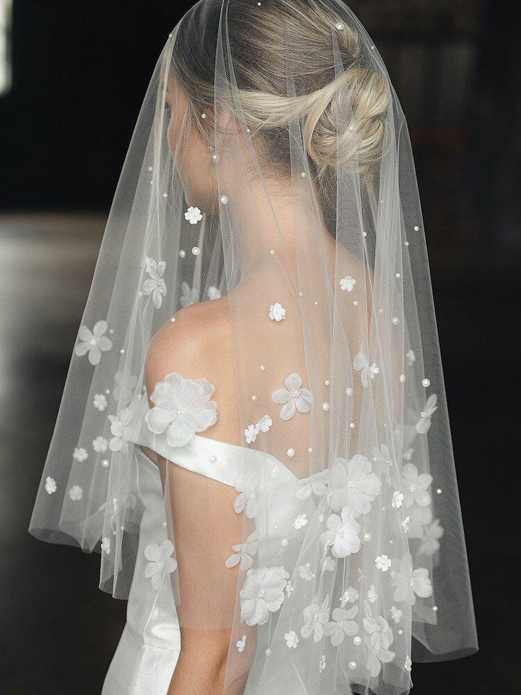 Model wears a short veil with floral embellishments and pearl accents. 