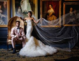 Bride and groom posing in front of vintage art photos