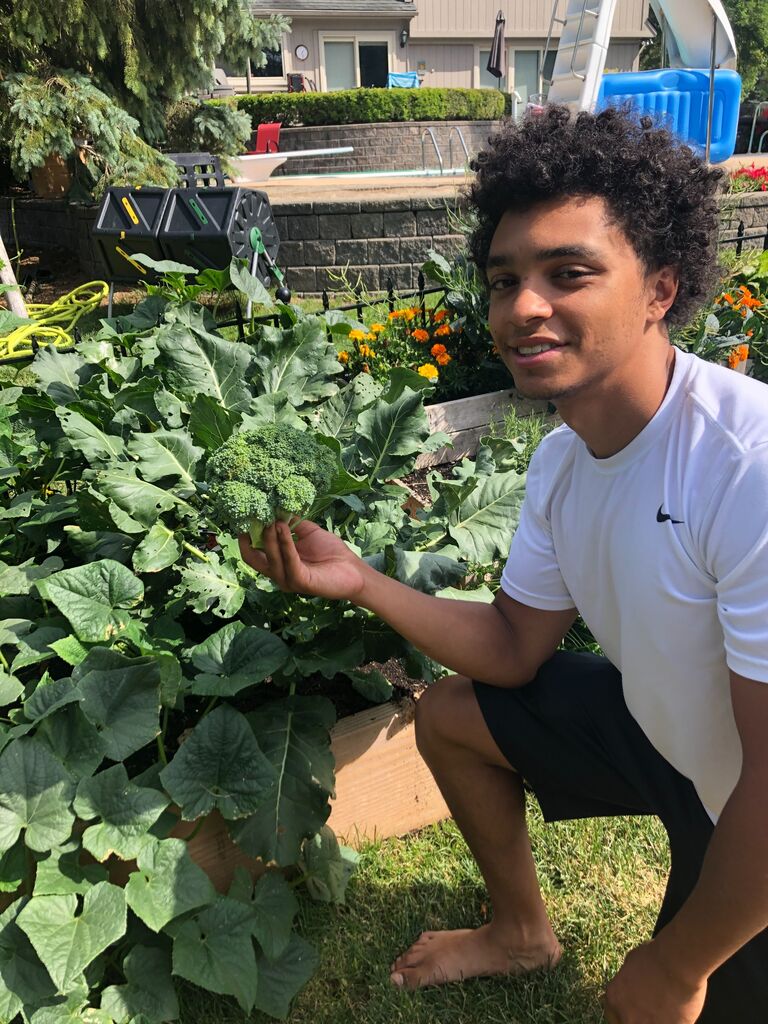 Zach with the first head of broccoli he's grown in his garden