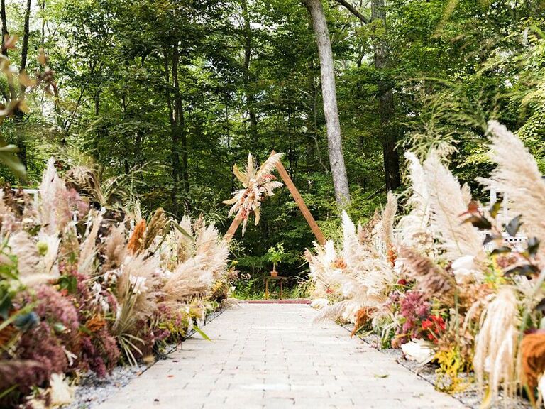 Lush pampas grass arrangements along outdoor wedding ceremony aisle and at altar