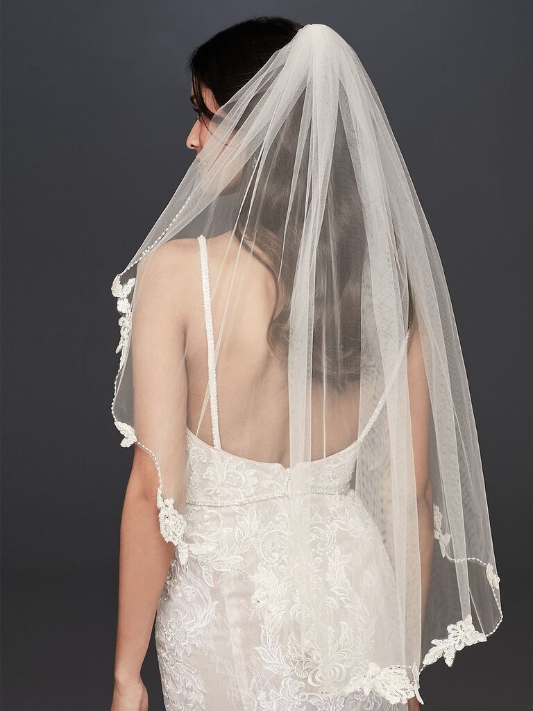 Model wears an elbow-length veil with floral trim. 