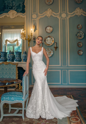 Femininely structured mermaid gown covered with exclusive beaded lace. It requires more that 140 hours of handwork to transform the material into a ready-to-wear bridal gown. A delicate heart shaped neckline with elegant wide straps and Boat low-back create feminine silhouette. The sheath trumpet skirt is decorated with Tulle pannels that pass into a magnificent chapel train. A lush Tulle overskirt decorated with sparkling lace is perfect for down-the-aisle entrance.