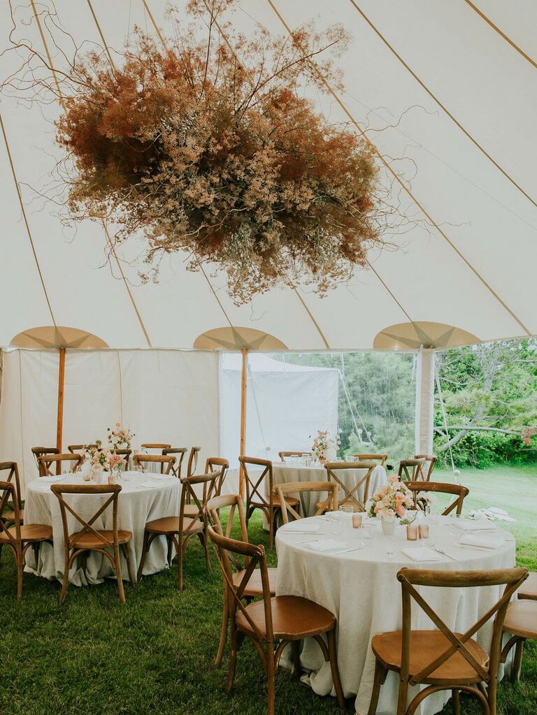 Neutral statement floral chandelier hanging from wedding tent