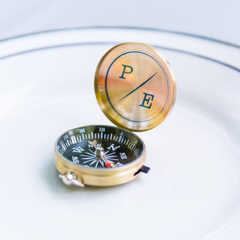 An opened gold compass with engraved initials
