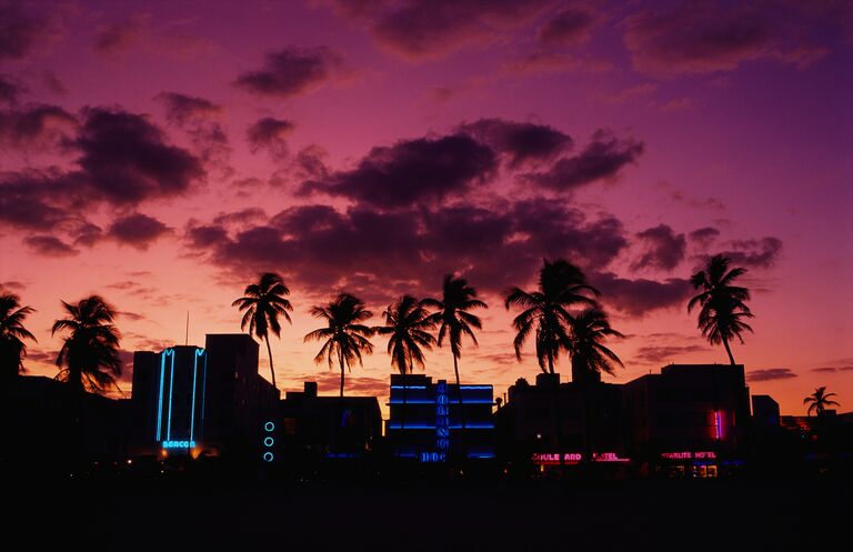 miami beach at dusk with purple and pink skies ocean drive in the distance with neon buildings
