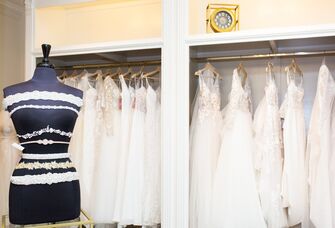 Mannequin in front of a rack of wedding dresses