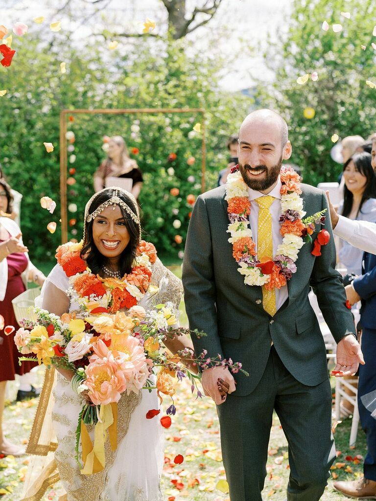 Bride and groom recessing down the aisle while wearing malas flower garlands.