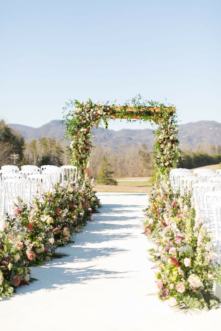 Outdoor wedding ceremony with greenery-lined aisle and mountain views