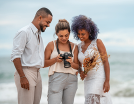 bride and groom with wedding photographer looking at camera