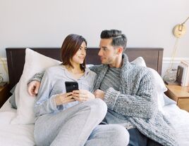 Engaged couple sitting on bed