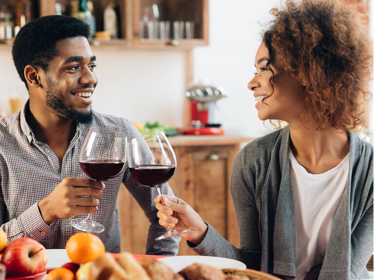 Couple toasting wine glasses containing red wine