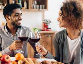 Couple toasting wine glasses containing red wine