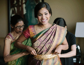 Bride's saree being draped by loved ones. 