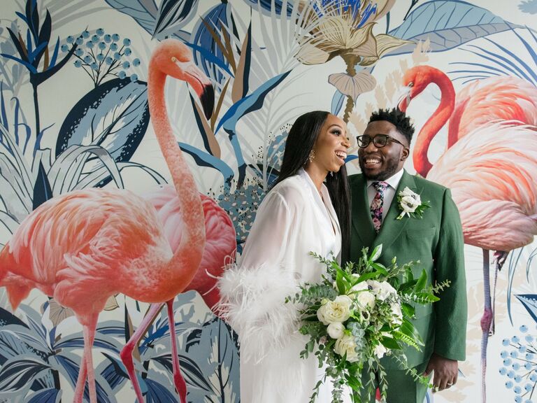 Couple wears their elopement attire while standing in front of a funky mural. 
