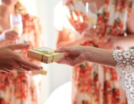 Bride giving bridesmaid gifts in wedding day robes