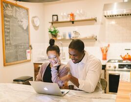 Engaged couple registering for gift cards on laptop at home