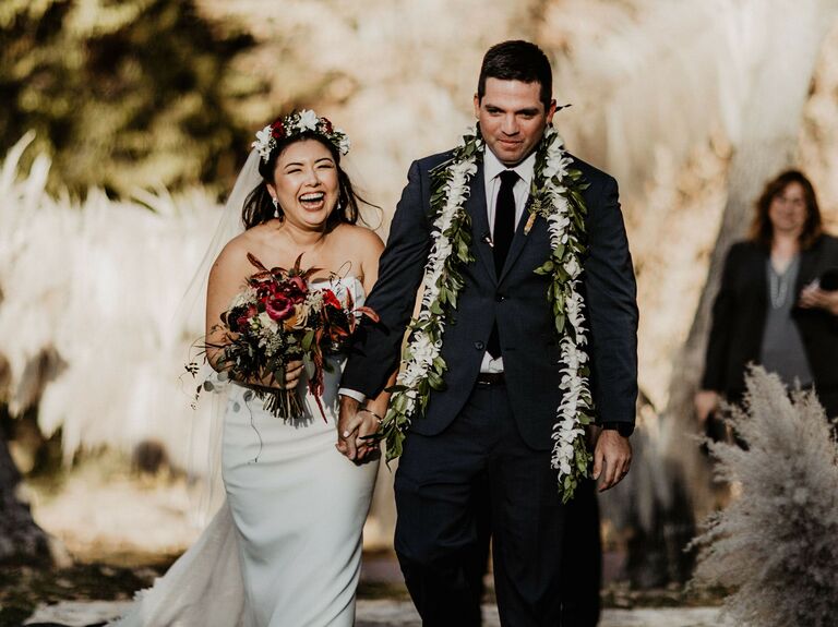 Bride and groom walking down the aisle wearing Hawaiian leis.