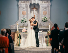 Bride and groom kissing at the altar on wedding day inside church