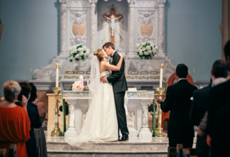 Bride and groom kissing at the altar on wedding day inside church