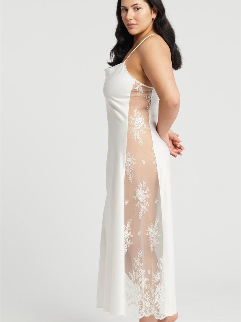 Model wears a long white silk nightgown with a lace side panel. 