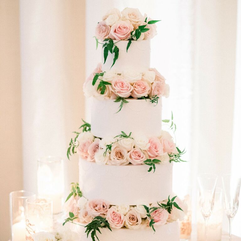 White four-tier cake with pink roses between each tier