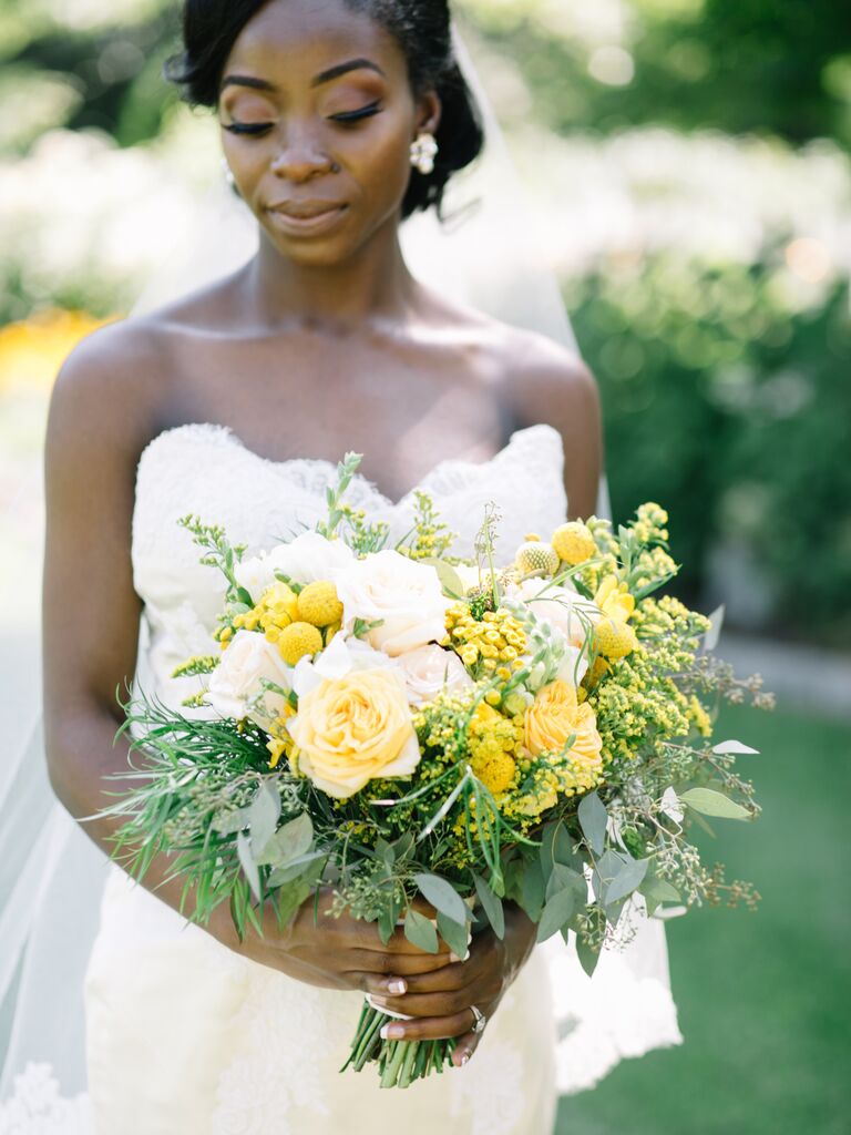 A bride walks down the aisle with a blooming bouquet in shades of vibrant yellow and brilliant white.