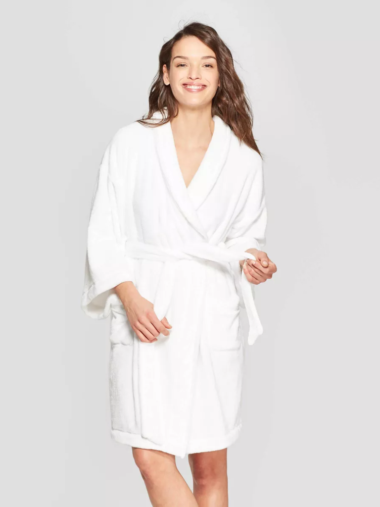 Model wearing a short plush robe with long sleeves and a chic waist tie