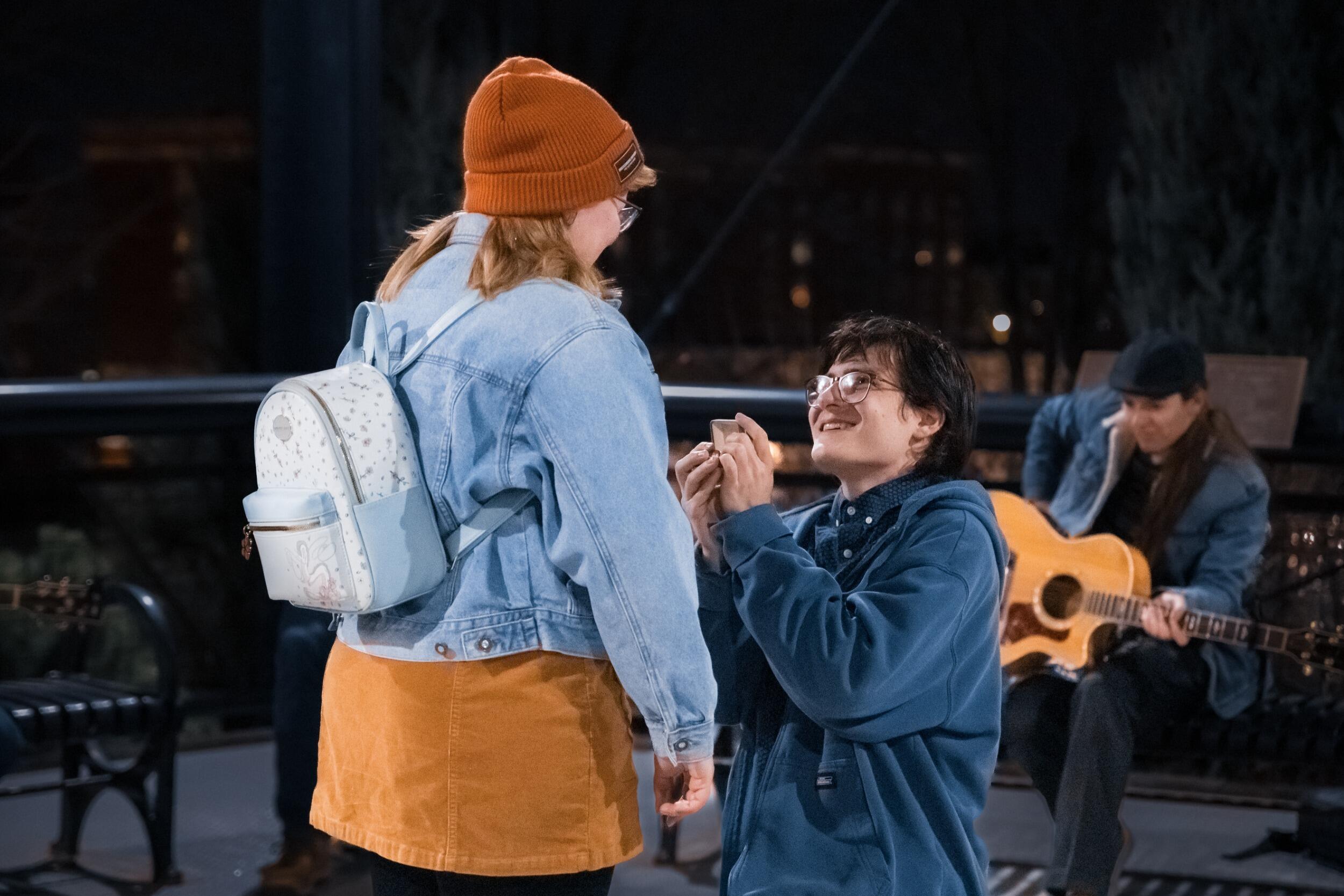 Blake took Jordyn on a winter date in Olde Town Arvada, he told her it was spontaneous (it very much was not). They started with viewing the Christmas Lights in Olde Town, went ice skating, and then "finished" the night with a pizza dinner. During dinner, the two of them discussed the times they thought the other was going to "pop the question". She admitted that she thought he was going to propose while they were ice skating. After dinner, Jordyn suggested they go to the Arvada Water Tower, where they had their first kiss and a frequent stop on their dates in Olde Town. Blake happily agreed, everything was going according to his plan. As they approached, Jordyn noticed some musicians setting up under the tower, she suggested they stay back and listen from afar as not to disturb them. Blake continued to pull her towards them. To Jordyn's surprise, it turned out to be their friends. At that point Blake revealed that her instincts were right. He began singing "Can't Help Falling in Love" by Elvis Presley. Blake and their friends had been preparing for months. He got down on one knee but little did he know that Jordyn had been carrying the ring she planned to give him. It was a cold December night but their loved warmed the air, it was perfect!