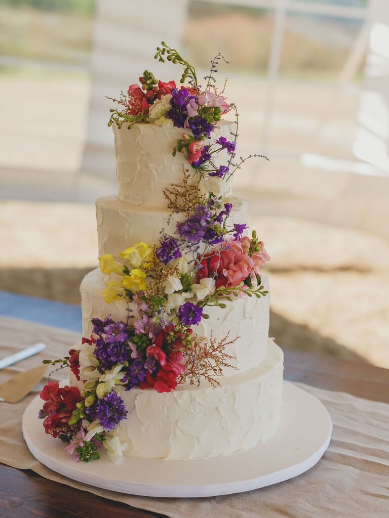 Four-tier white rustic wedding cake with cascading wildflowers
